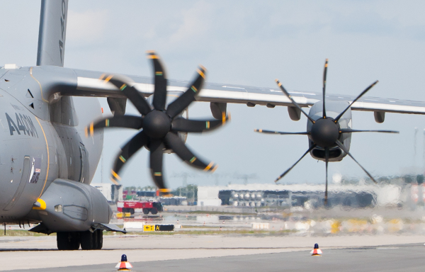 a military aircraft shows one propeller being feathered while the other is still operating