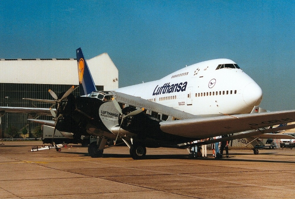 a ju 52 sits in front of a Lufthansa 747